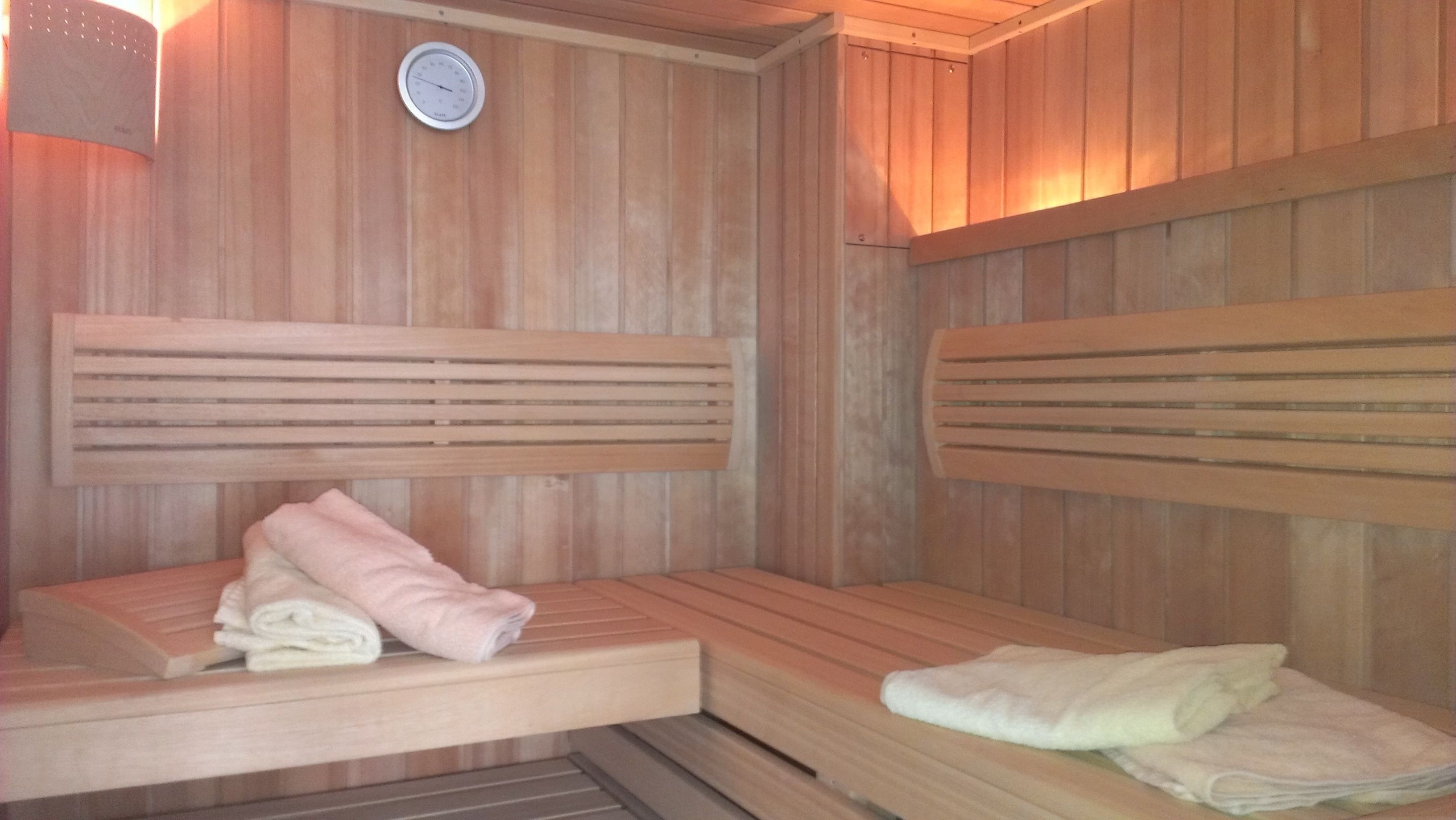 Un sauna avec des bancs en bois et une horloge fixée au mur.