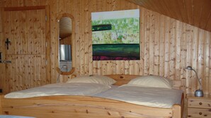 A wooden-paneled room with a bed, a nightstand, a lamp, and a painting on the wall. - Pension Haus Diefenbach (Heimbach)