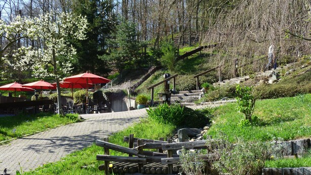 A park with wooden benches, red umbrellas, and a stone staircase leading up a hill. - Pension Haus Diefenbach (Heimbach)