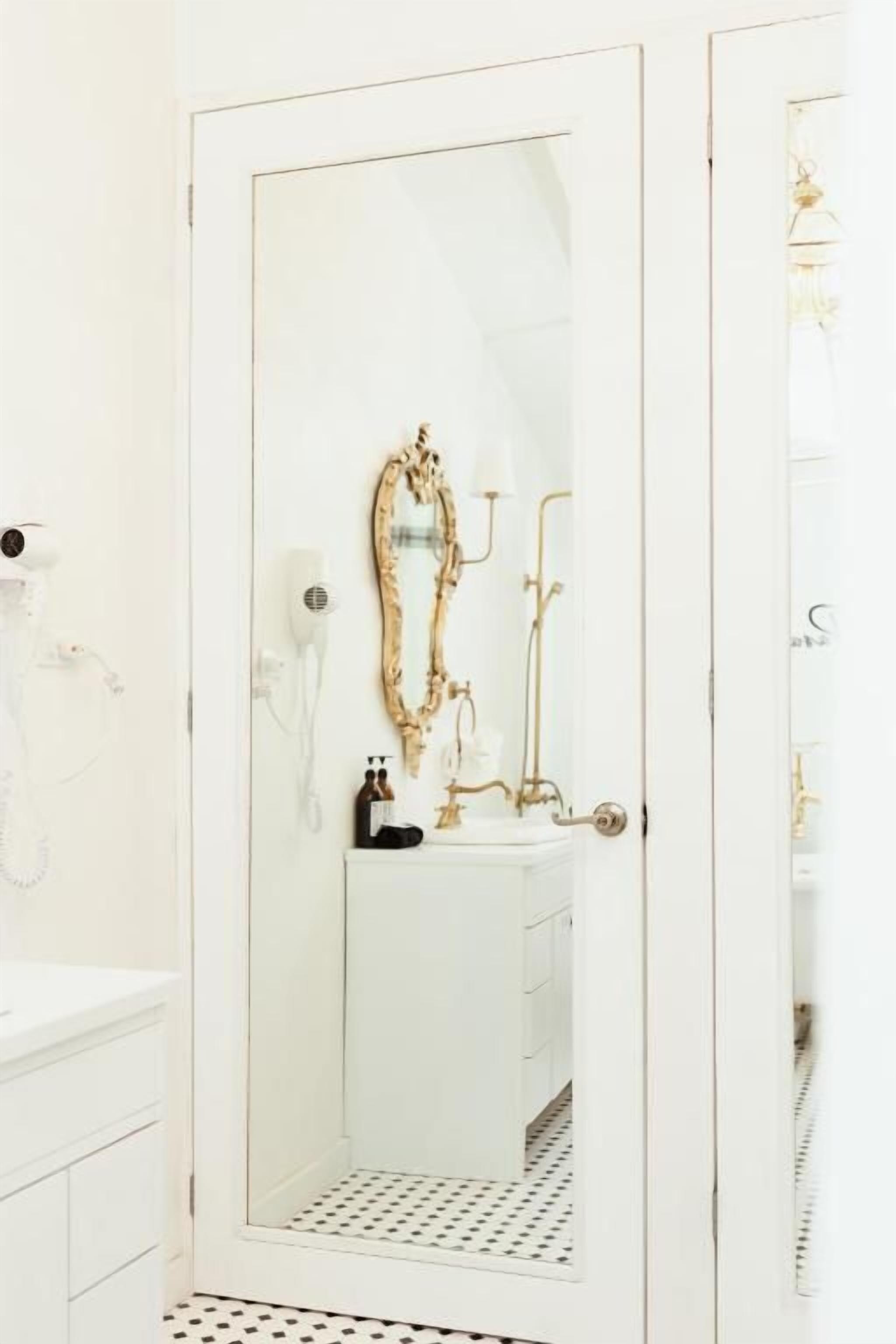 Un baño con tocador blanco, un espejo con marco dorado y zona de ducha.