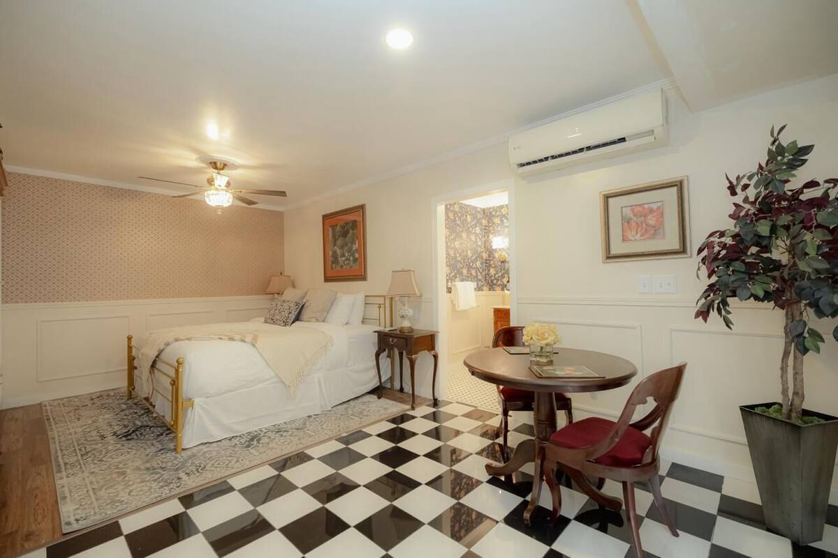 Une chambre à coucher comprenant un lit, une table de chevet, une lampe et une petite table à manger avec des chaises.