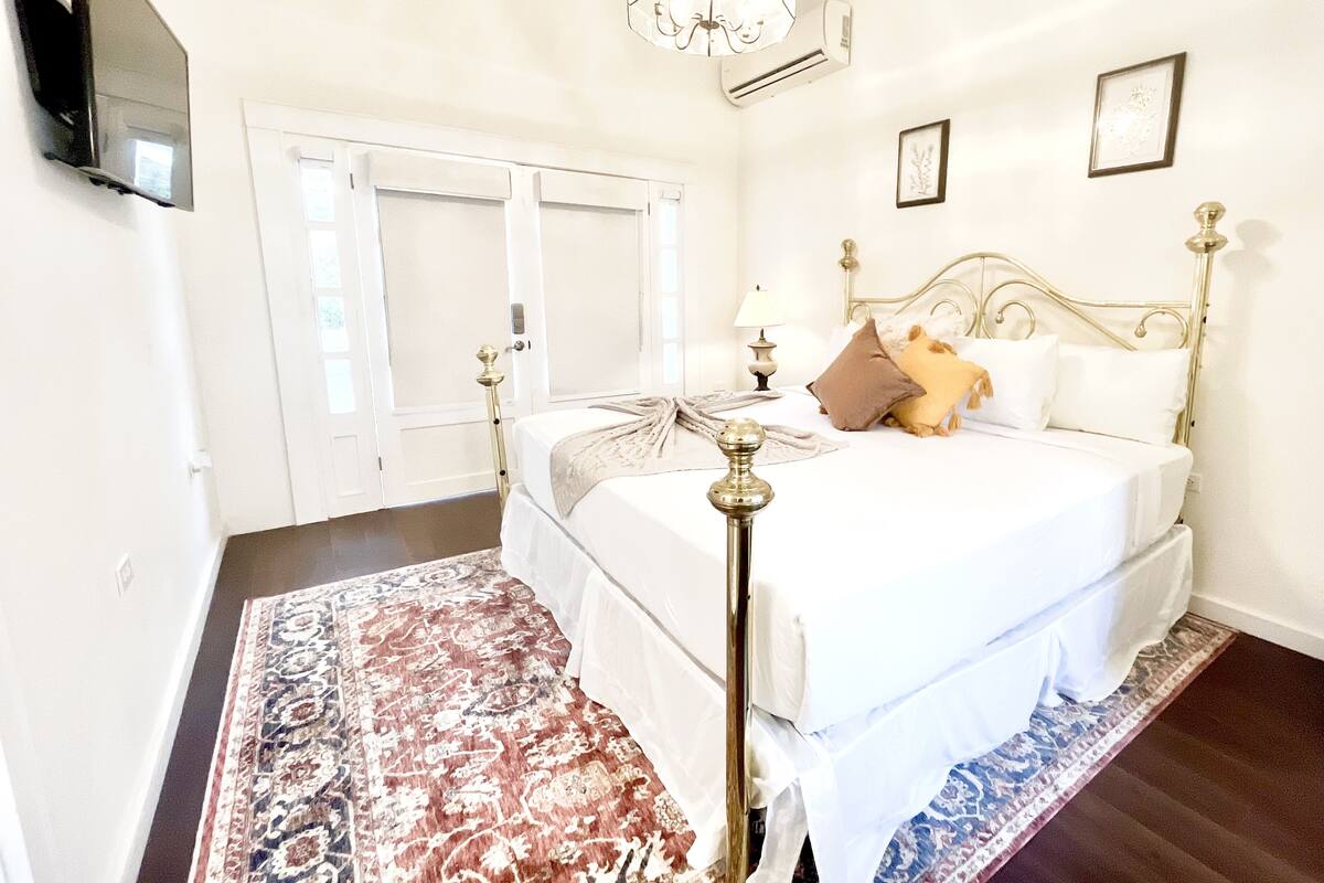 Une chambre à coucher avec un lit, un lustre, une table de chevet et un grand tapis.