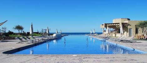 Alberca al aire libre, sombrillas en la alberca y camastros