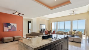 A modern living room with a large island, seating area, and a view of the ocean. - Encanto Living 1201 -4BR by Kivoya (Puerto Peñasco)