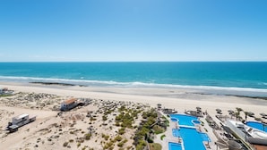 A resort with a beach view, multiple swimming pools, and a clear blue sky. - Encanto Living 1201 -4BR by Kivoya (Puerto Peñasco)