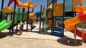 A playground with various play structures including slides, climbing areas, and swings.
