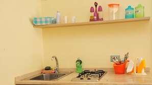 A kitchen with a sink, stove, and various kitchen utensils and containers on the countertop. - Camere Sulle Mura (Otranto)