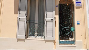 A building with a balcony, a window with shutters, and a door with a number plate. - Camere Sulle Mura (Otranto)