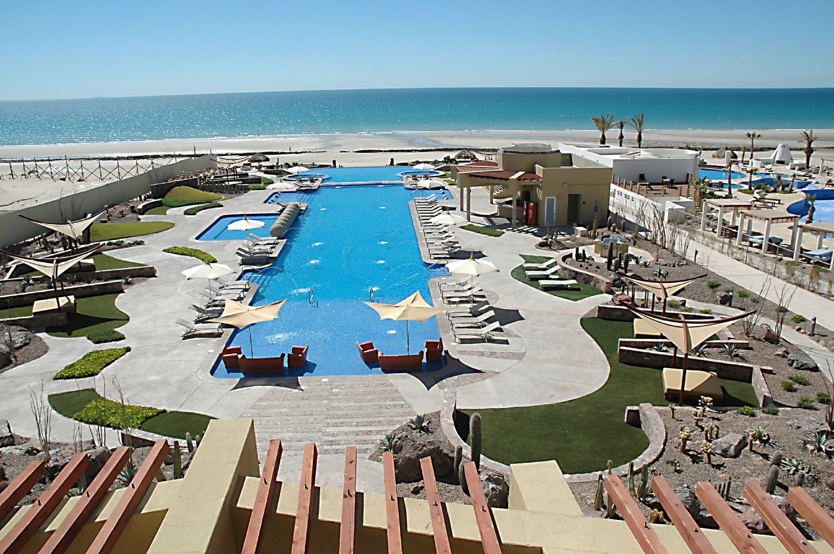 Un resort con una grande piscina centrale, diverse piscine più piccole e vista sulla spiaggia.