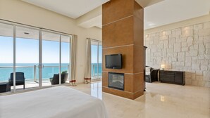 A spacious bedroom with a large bed, a fireplace, a television, and a balcony with a view of the sea. - Encanto Living 1202 -4BR by Kivoya (Puerto Peñasco)