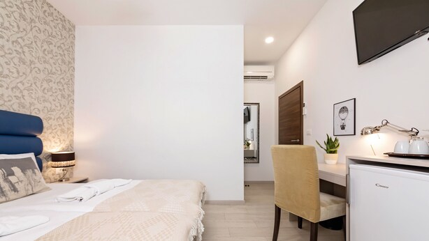 Un dormitorio con cama, mesita de noche, lámpara y escritorio con silla.