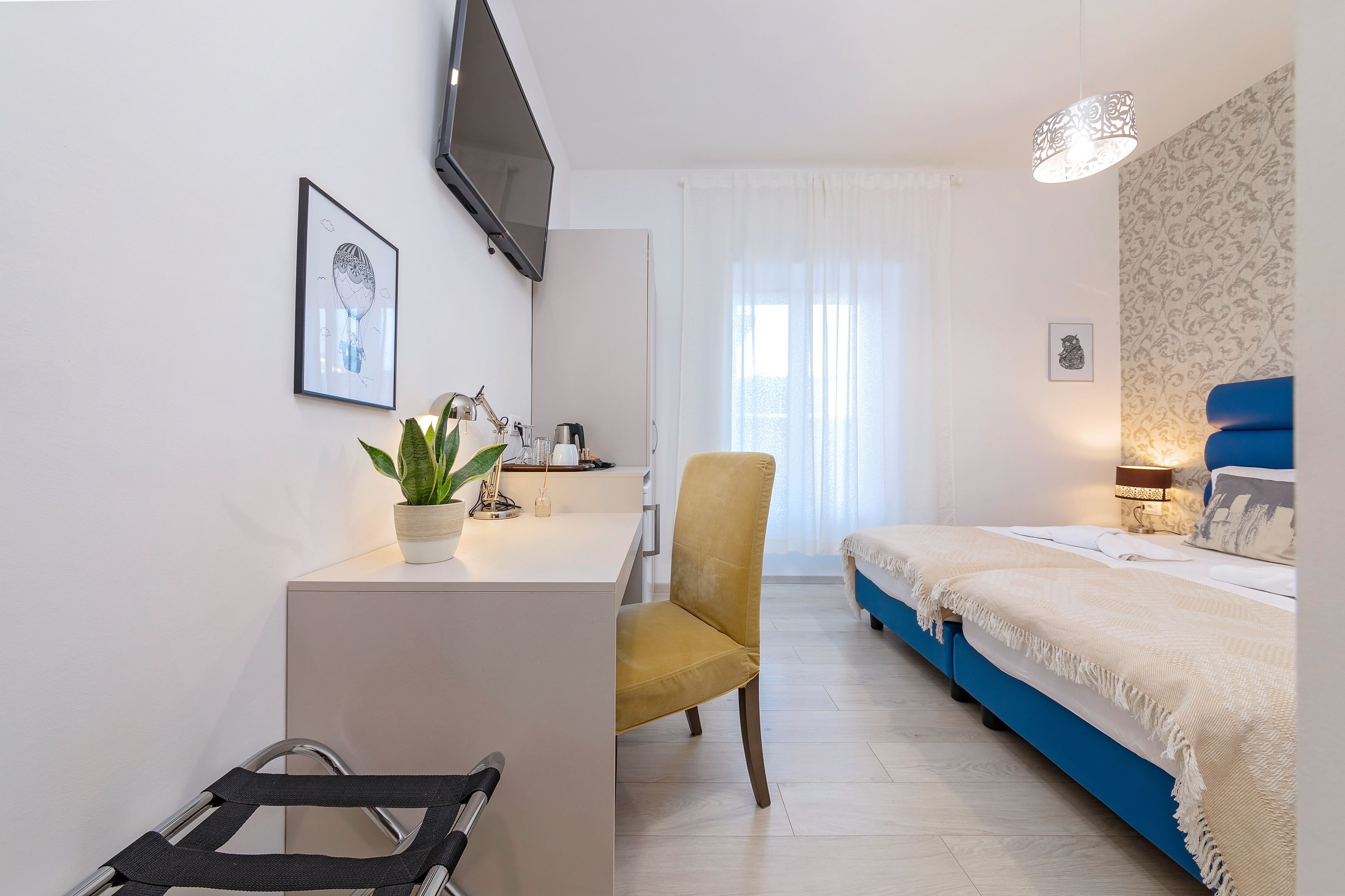 Una habitación de hotel moderna con escritorio, silla, cama y televisor en la pared.