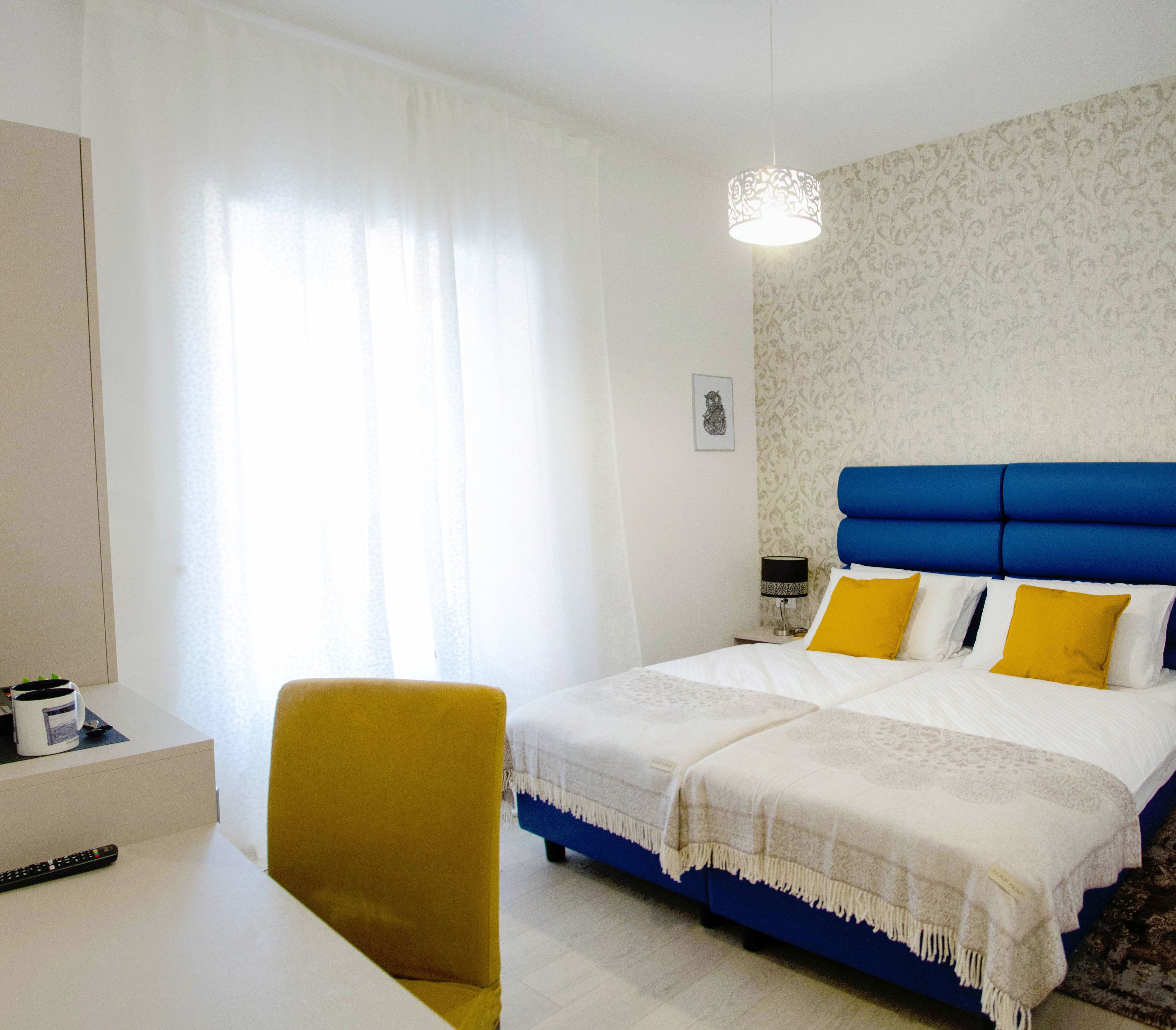 A hotel room with a bed, a desk, a chair, and a lamp.