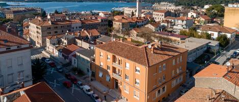 A coastal cityscape with historic buildings, a prominent tower, and a clear view of the sea.