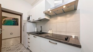 Una cocina moderna con armarios blancos, encimera negra y campana extractora de acero inoxidable.
