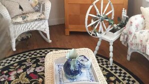Una habitación acogedora con una silla de mimbre, un aparador de madera y una mesita con un objeto decorativo.