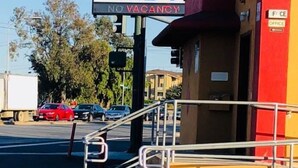 A Bayshore Inn sign, a red and yellow building, and a traffic light. - Bayshore Inn (San Jose)