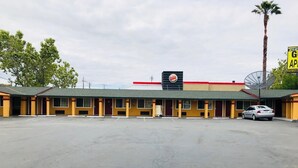 A motel with a Burger King sign, a parking lot, and a palm tree. - Bayshore Inn (San Jose)
