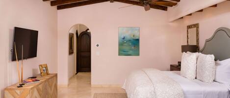 A bedroom with a bed, a TV, a painting, and a wooden cabinet.