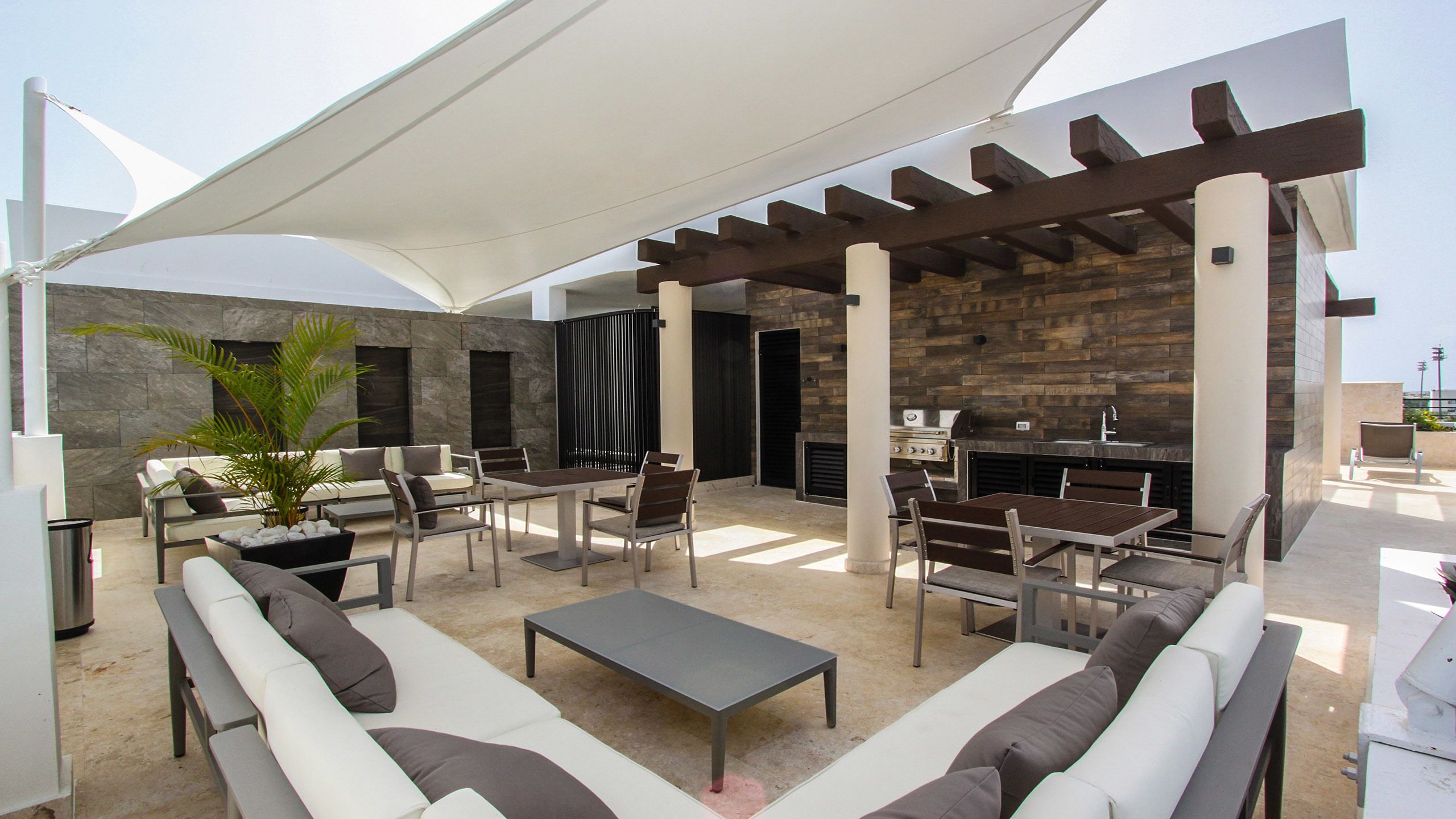 An outdoor patio with a pergola, seating area, and a built-in grill.