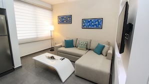 Een moderne woonkamer met een bank, een witte salontafel en twee aan de muur hangende schilderijen.