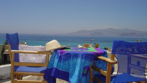 Une table recouverte d’une nappe colorée, deux chaises et un chapeau de paille posés sur la table.