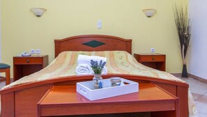 Un lit bien fait, agrémenté d’un plateau décoratif, d’un vase avec des fleurs et d’une petite plante posée sur une table de chevet.