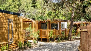 Eine Holzhütte mit Balkon, umgeben von Bäumen und Vegetation.