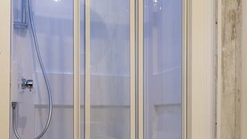 A modern bathroom with a glass shower enclosure, a toilet, and a sink.