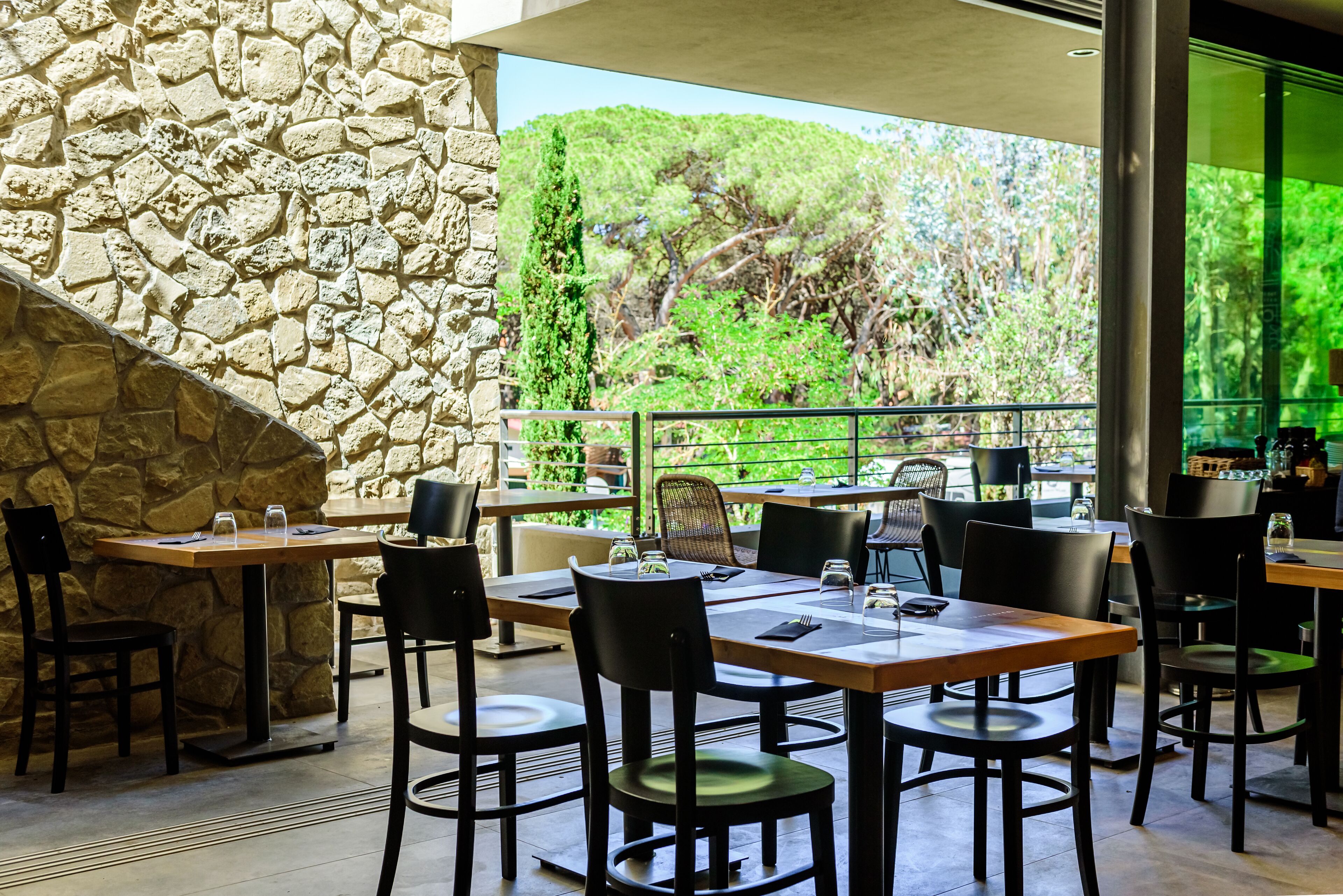 An outdoor dining area with stone walls, multiple tables, and chairs.