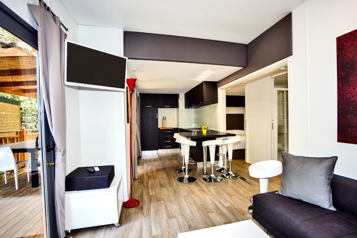 Een moderne keuken met een centraal eiland, barstoelen en een eettafel.