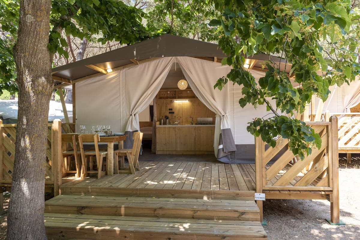 Een houten terras met een overdekte eethoek, een keuken en een zithoek.