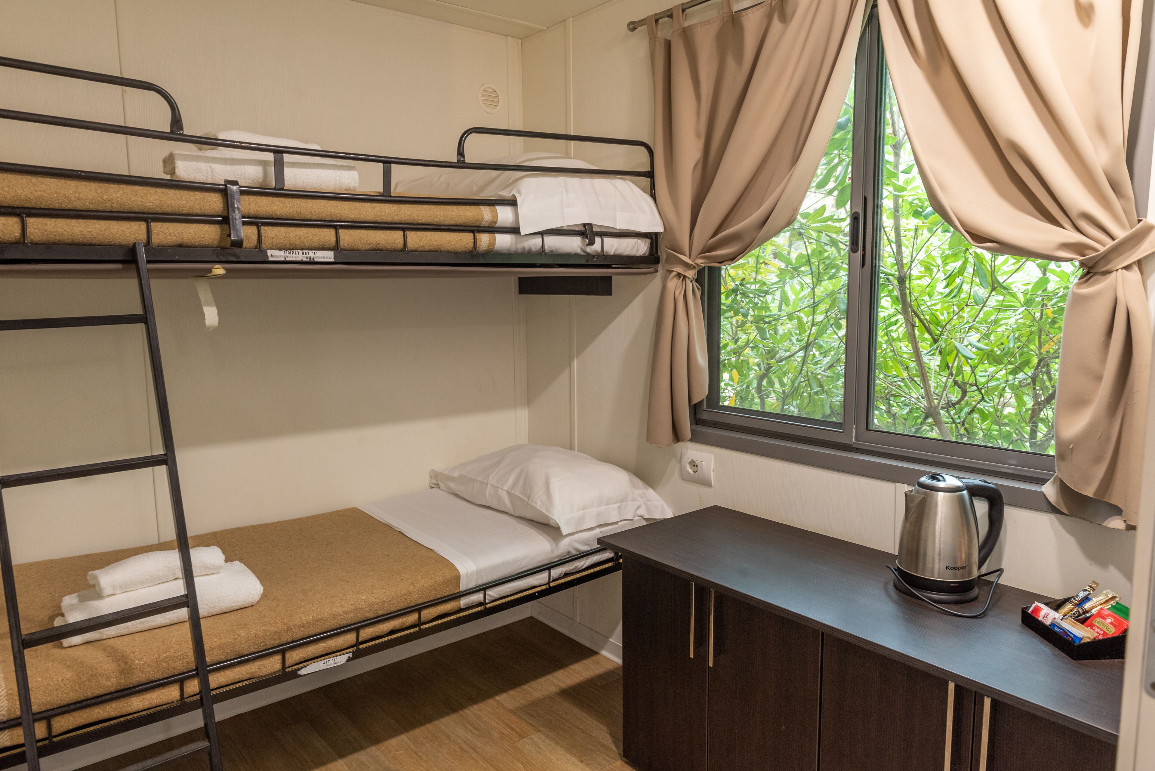 Un lit superposé avec un petit bureau et une bouilloire.