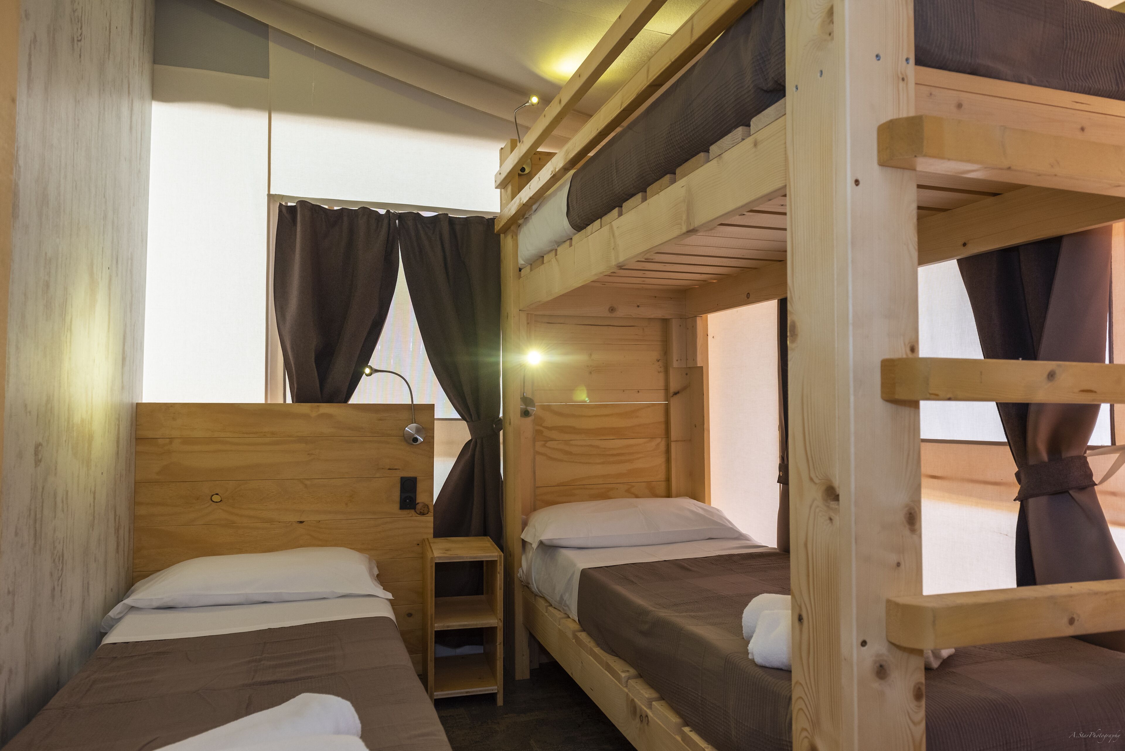 Habitación con literas, paredes de madera y ventana con cortinas.