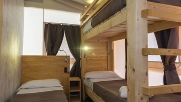 Habitación con literas, paredes de madera y ventana con cortinas.