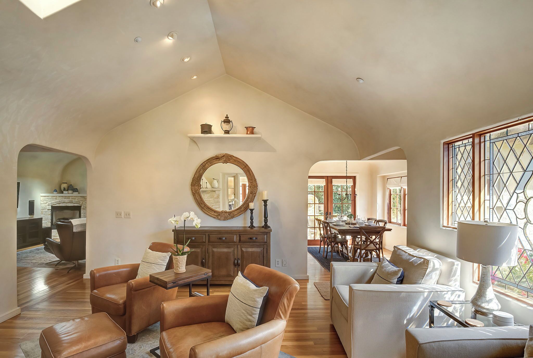 A spacious living room with leather sofas, a wooden dining table, and a large mirror on the wall.