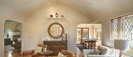A spacious living room with leather sofas, a wooden dining table, and a large mirror on the wall.