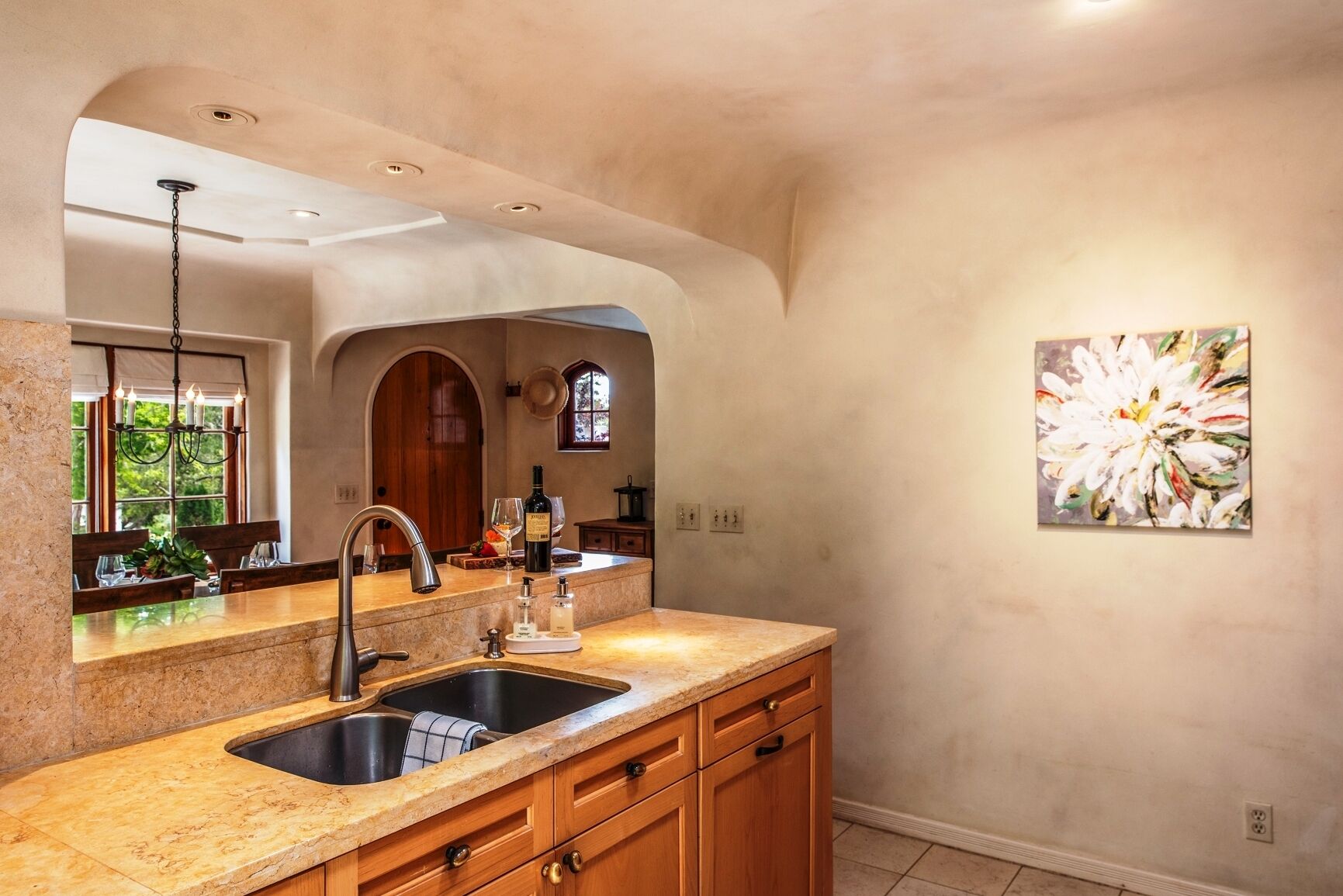 A kitchen with granite countertops, a double sink, wooden cabinets, and a pendant light.