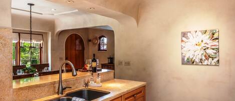 A kitchen with granite countertops, a double sink, wooden cabinets, and a pendant light.