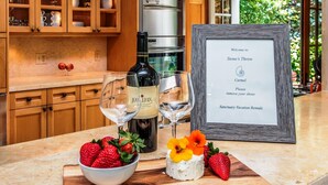 A kitchen counter with a bottle of wine, glasses, strawberries, and a framed welcome sign. - 3770 Stone's Throw ~ Walk to the Ocean and Town (Carmel)