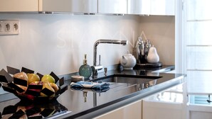 A modern kitchen with a black countertop, stainless steel sink, and white cabinets. - Chez Aynur 2 bedroom apartment VRBO (Nice)