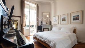 A hotel room with a piano, a bed, a fireplace, and framed pictures on the wall. - Chez Aynur 2 bedroom apartment VRBO (Nice)