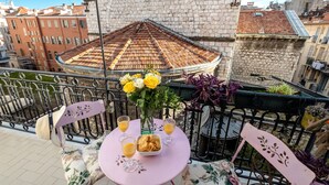 A balcony with a table set for two, featuring a vase with flowers and glasses of a beverage. - Chez Aynur 2 bedroom apartment VRBO (Nice)