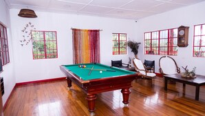 A room with a pool table, wooden flooring, and large windows with red frames. - Lodge Paraiso Verde Manizales (Manizales)