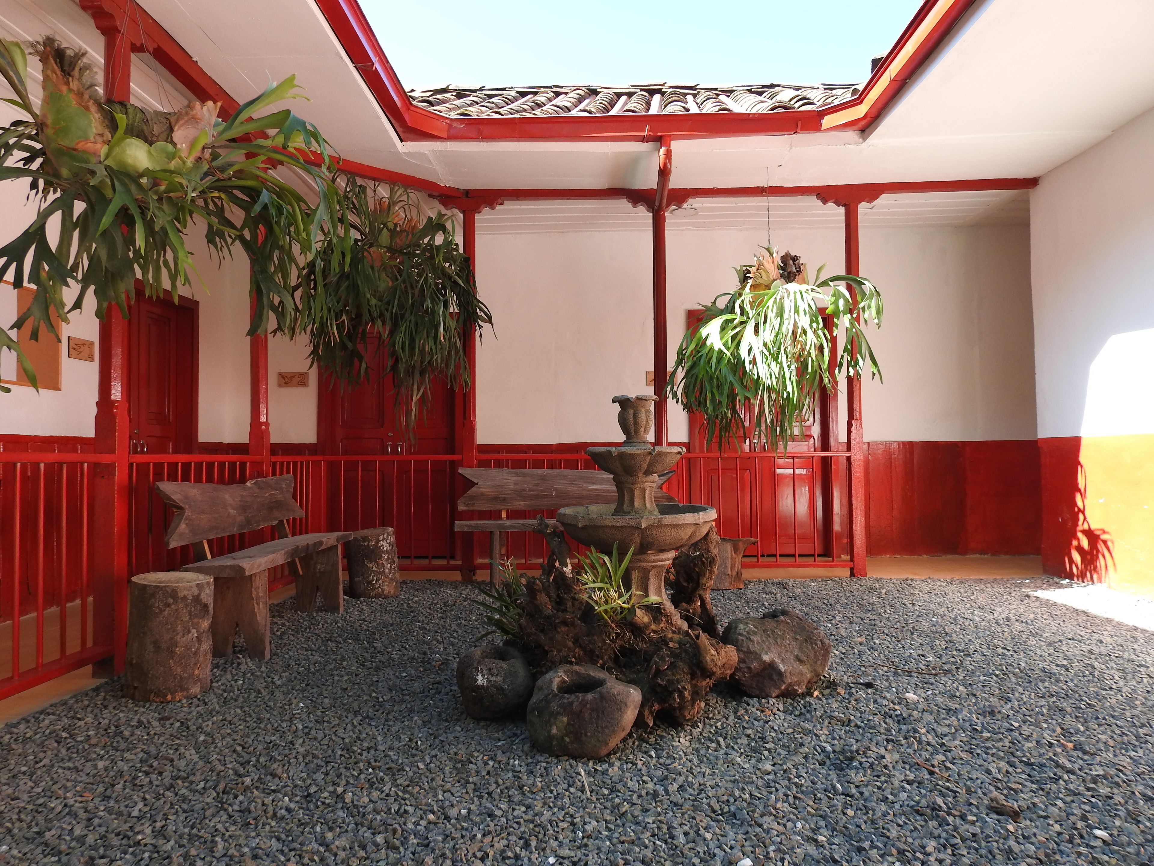 A courtyard with a red and white building, a fountain, and various plants.