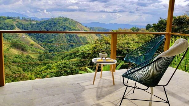 A balcony with a view of a lush valley and distant mountains. - Lodge Paraiso Verde Manizales (Manizales)