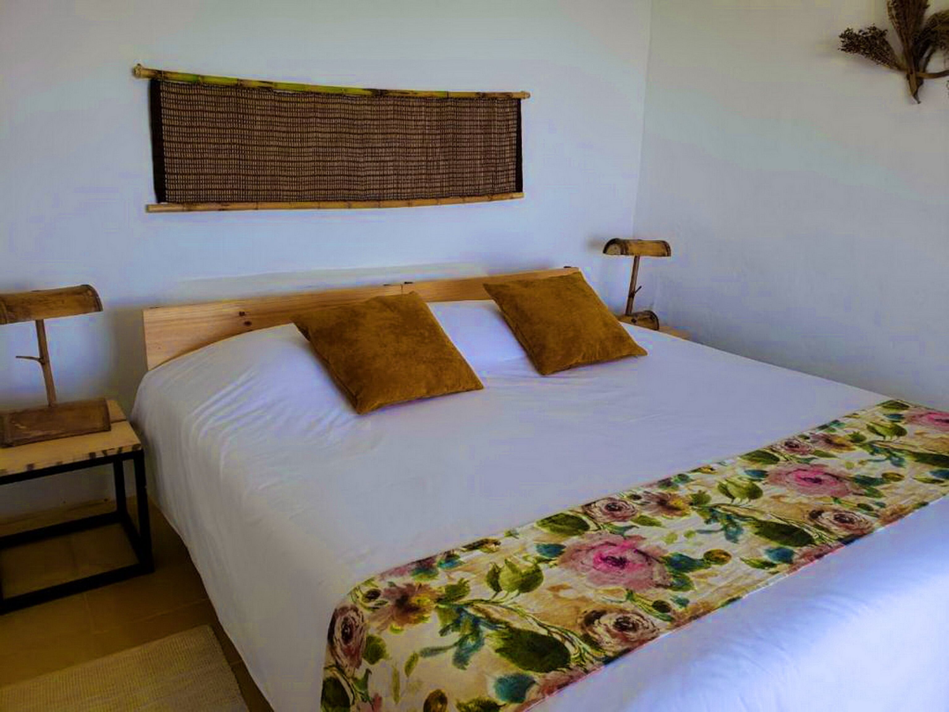 Un lit bien fait, avec deux oreillers, une tête de lit en bois et une couvre-lit à motifs floraux.