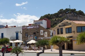 Une rue bordée d’immeubles, avec des terrasses et des palmiers.