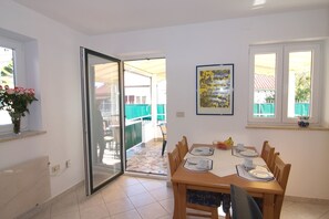 A dining area with a table set for four, a sliding glass door leading to an outdoor patio, and a framed artwork on the wall.