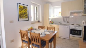 Une cuisine compacte avec un coin repas, comprenant une cuisinière, un four et un évier.